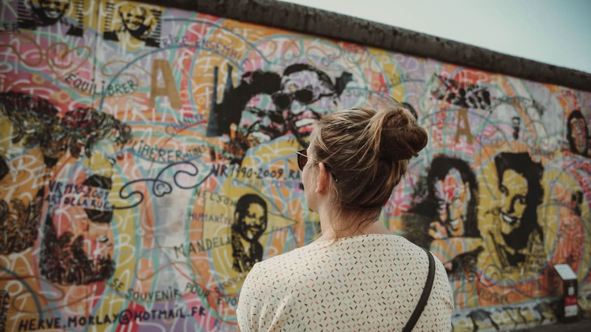 A visitor looking at a painted section of the Berlin Wall
