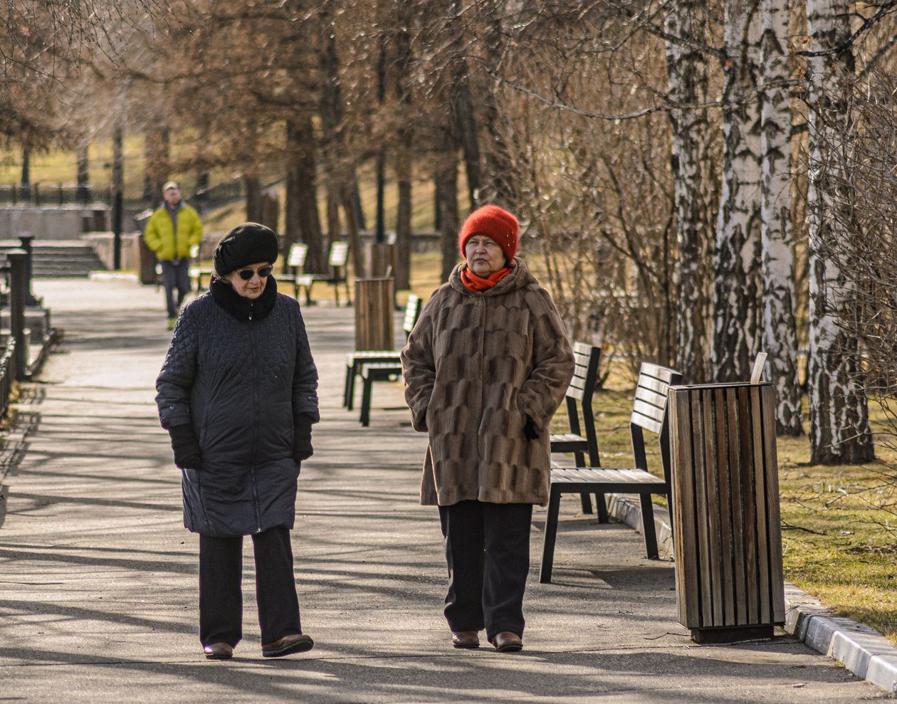 Two older women walking through a park in early spring