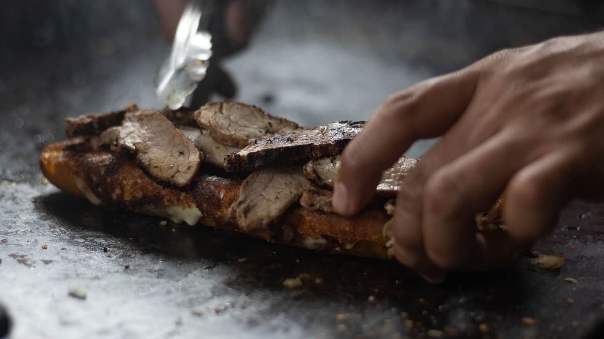 Sliced grilled meat on a sandwich roll on a hot plate