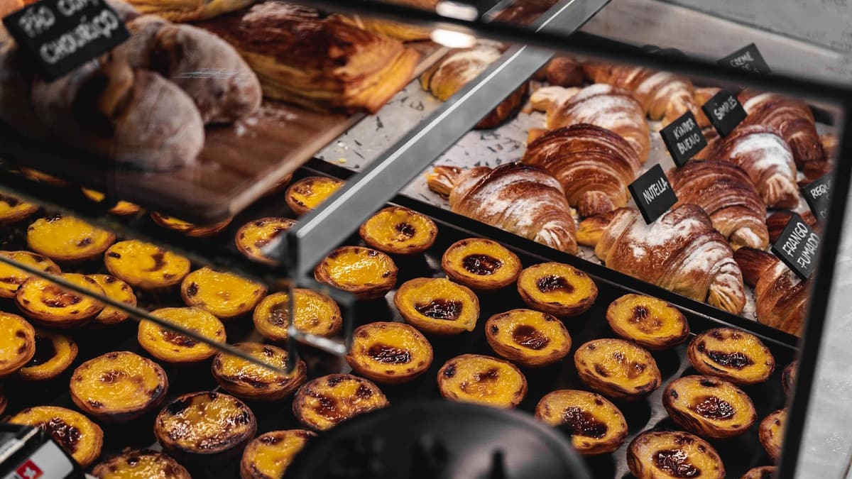 Pastry case in a Lisbon bakery with custard tarts and croissants