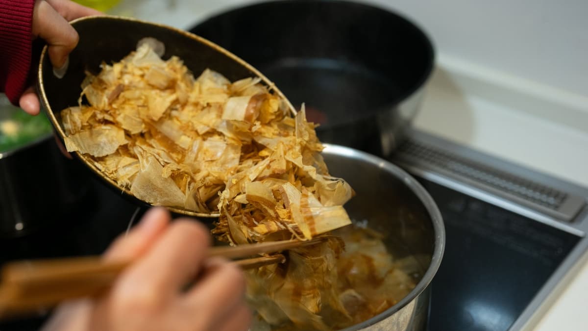 Bonito flakes going into a pot of dashi