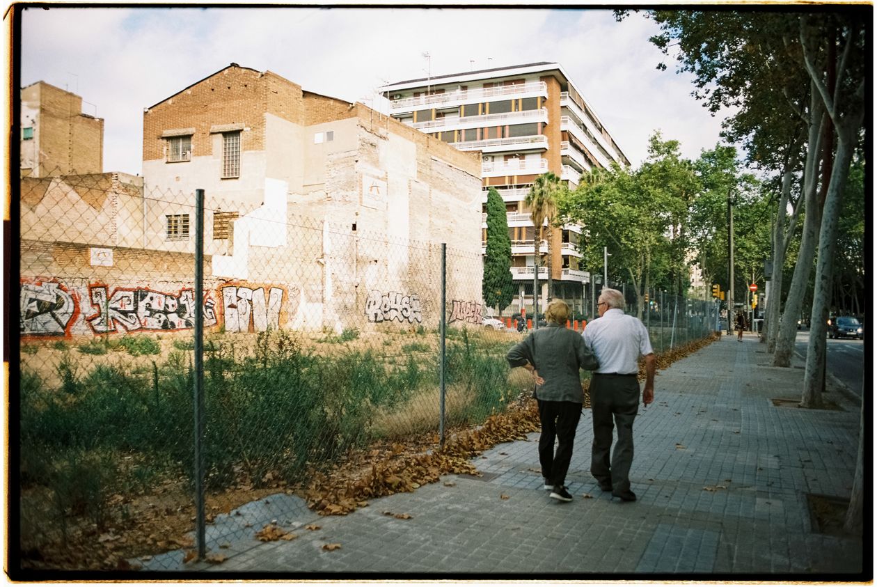 An older couple walking side by side along a city pavement